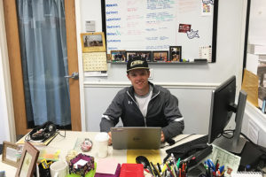 Steven Hansen '20 smiles while sitting at a desk. 