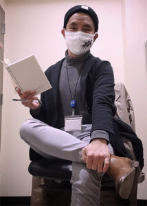 Jerome Viloria ’16 sitting on a chair holding a book.