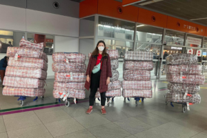 Olesya Korpan stands with bags of supplies in front of the airport