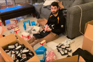 Todd Gable '15 sits on his living room floor with boxes of supplies