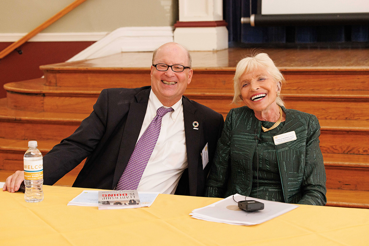 Michael Hoffman and Pamela Newman pose together while sitting at a table during the Center for Leadership inaugural summit