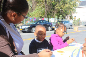 Two children taught to draw by a volunteer. 