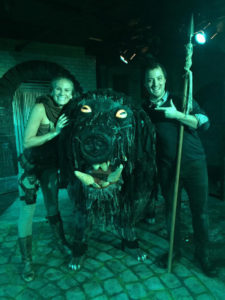 Two RMTG actors pose with a beast costume on stage. 