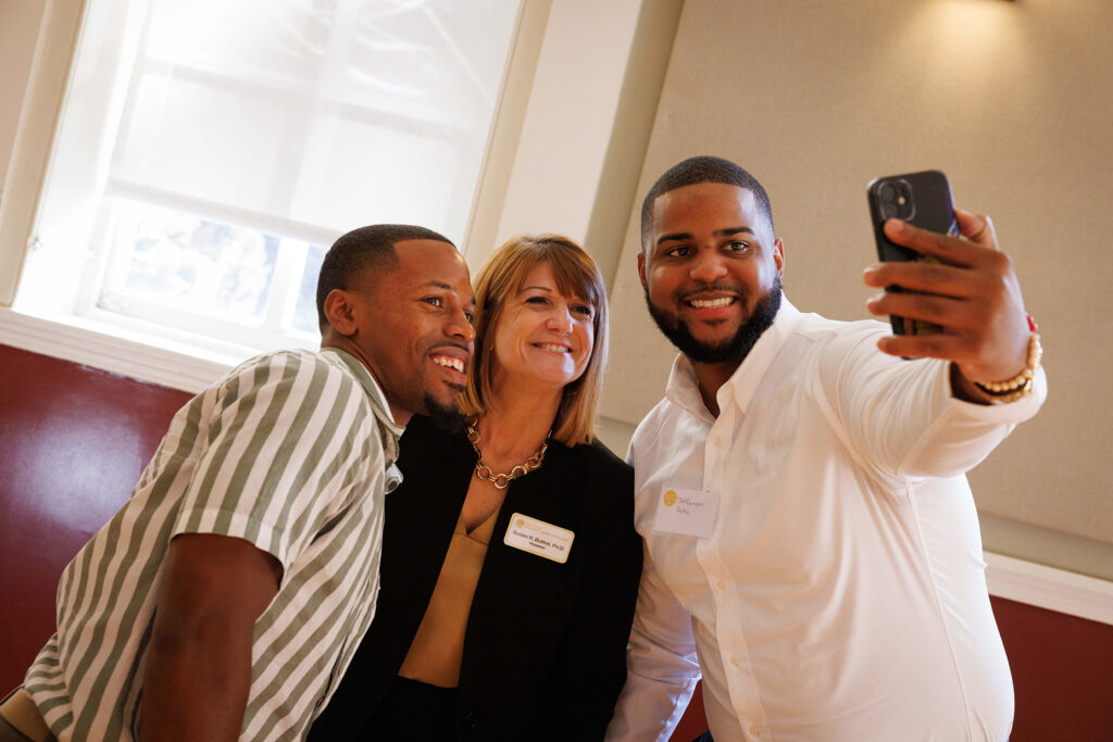 President Susan Burns smiles with two students as they take a selfie on their iPhone.