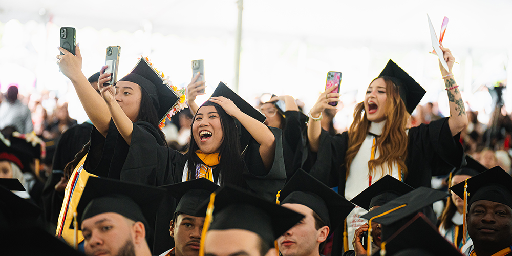 Photo of College of Mount Saint graduates cheering under the commencement tent and in their graduation regalia.